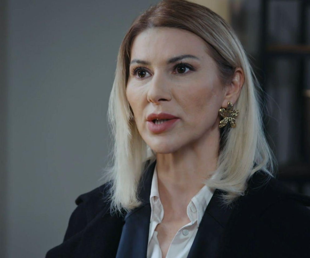 Blondynka w ciemnym płaszczu mówi z powagą. O intrygach w serialu Dziedzictwo przeczytasz w serwisie Eska.
