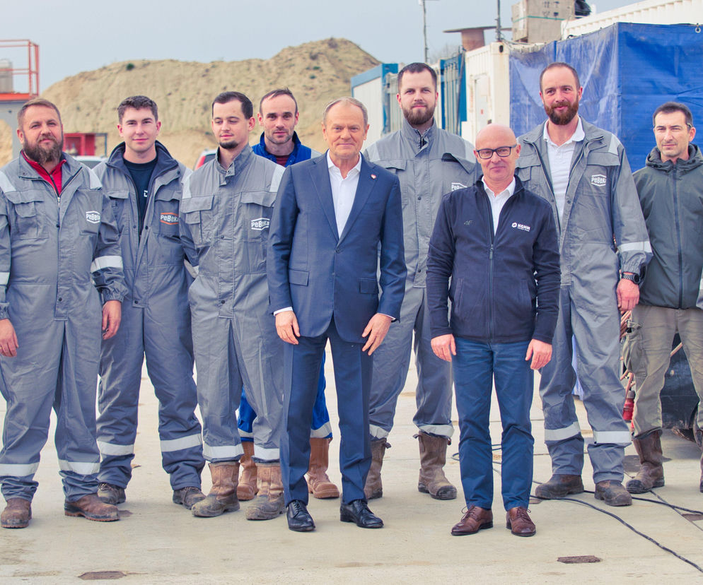 Donald Tusk i Wojciech Balczun w towarzystwie pracowników KGHM i PeBeKa podczas wizyty na placu budowy szybu Retków. Mężczyźni w ochronnych kombinezonach, Premier w garniturze. O tym, jak strategiczne inwestycje KGHM wpływają na rozwój polskiej gospodarki, przeczytasz na Super Biznes.