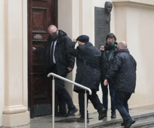 Pięciu ochroniarzy prowadzi Kaczyńskiego do bramy