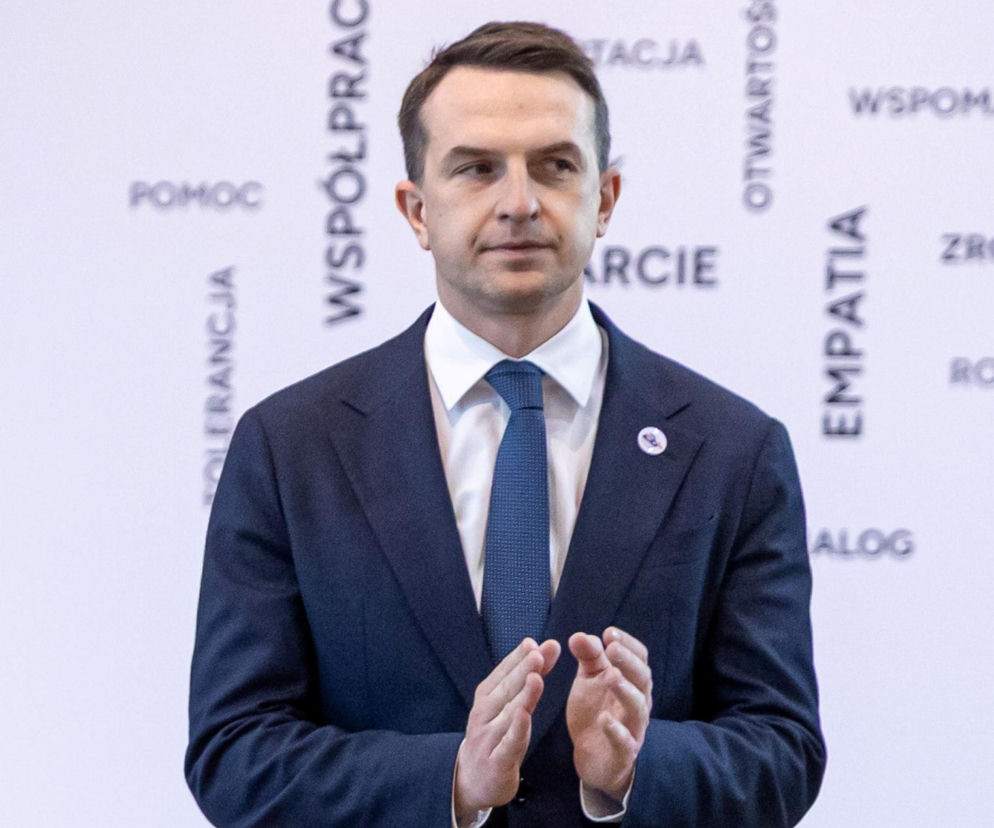 Adam Szłapka w garniturze klaszcze na tle napisu Empatia. O reakcji rządu na słowa Carlsona przeczytasz na SE Polityka.