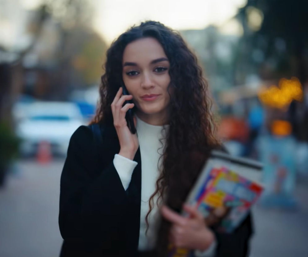 Kobieta o długich, kręconych włosach rozmawia przez telefon. O losach bohaterów Dziedzictwa czytaj w SE Superseriale.