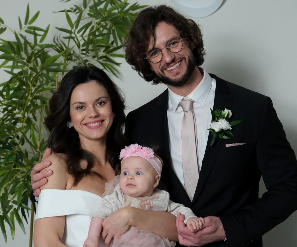 Paulina Lasota (Kasia) i Mateusz Mosiewicz (Mariusz) z dzieckiem na rękach, pozujący do zdjęcia po ślubie w urzędzie, uśmiechnięci. Artykuł o ich ślubie i brakujących gościach przeczytasz na stronie Super Seriale.