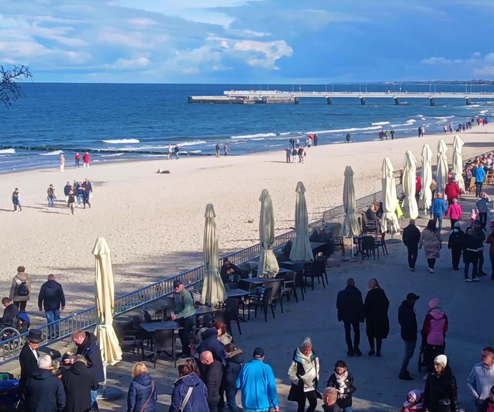 Tłumy turystów spacerujące promenadą przy plaży w Kołobrzegu. O darmowym wstępie na molo przeczytasz na Eska Koszalin.
