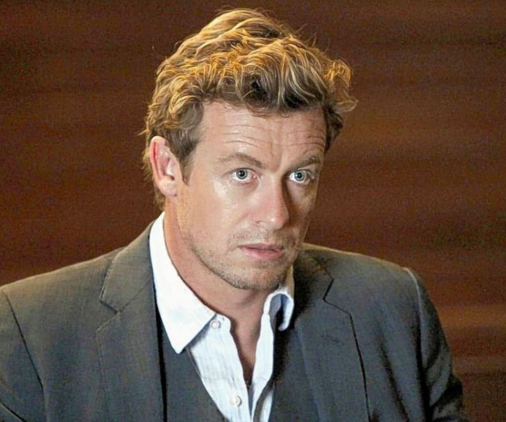 Portret Patricka Jane'a (Simon Baker) z serialu Mentalista w szarym garniturze i białej koszuli, patrzącego prosto przed siebie. Jest to postać, wokół której skupiają się wydarzenia w serialu. Możesz przeczytać o nim na Super Seriale.