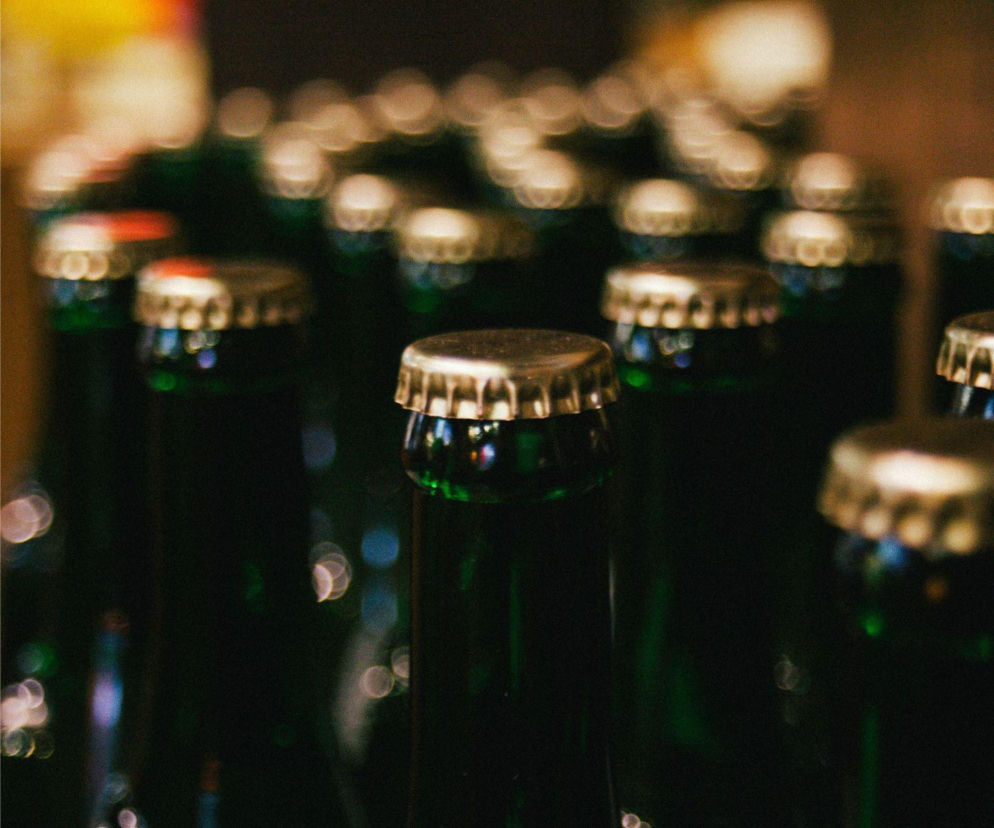 Butelki piwa z kapslami, symbolizujące branżę piwowarską w kryzysie i planowane zwolnienia w koncernie Heineken. Więcej o redukcji etatów i wpływie sztucznej inteligencji na rynku pracy przeczytasz na portalu Super Biznes.