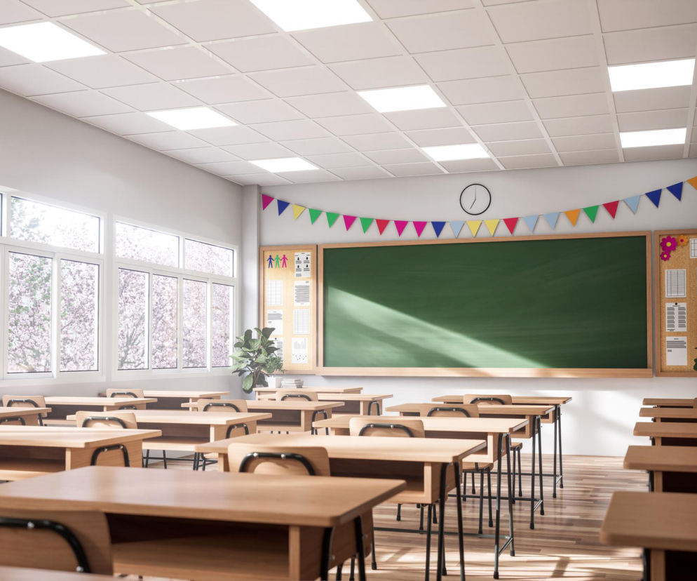 Pusta klasa szkolna z drewnianymi ławkami, krzesłami i zieloną tablicą, symbolizująca miejsca zdarzeń, gdzie urazy głowy, takie jak wstrząśnienie mózgu u dziecka, mogą prowadzić do tragicznych konsekwencji. O konsekwencjach urazów głowy przeczytasz na Poradnik Zdrowie.