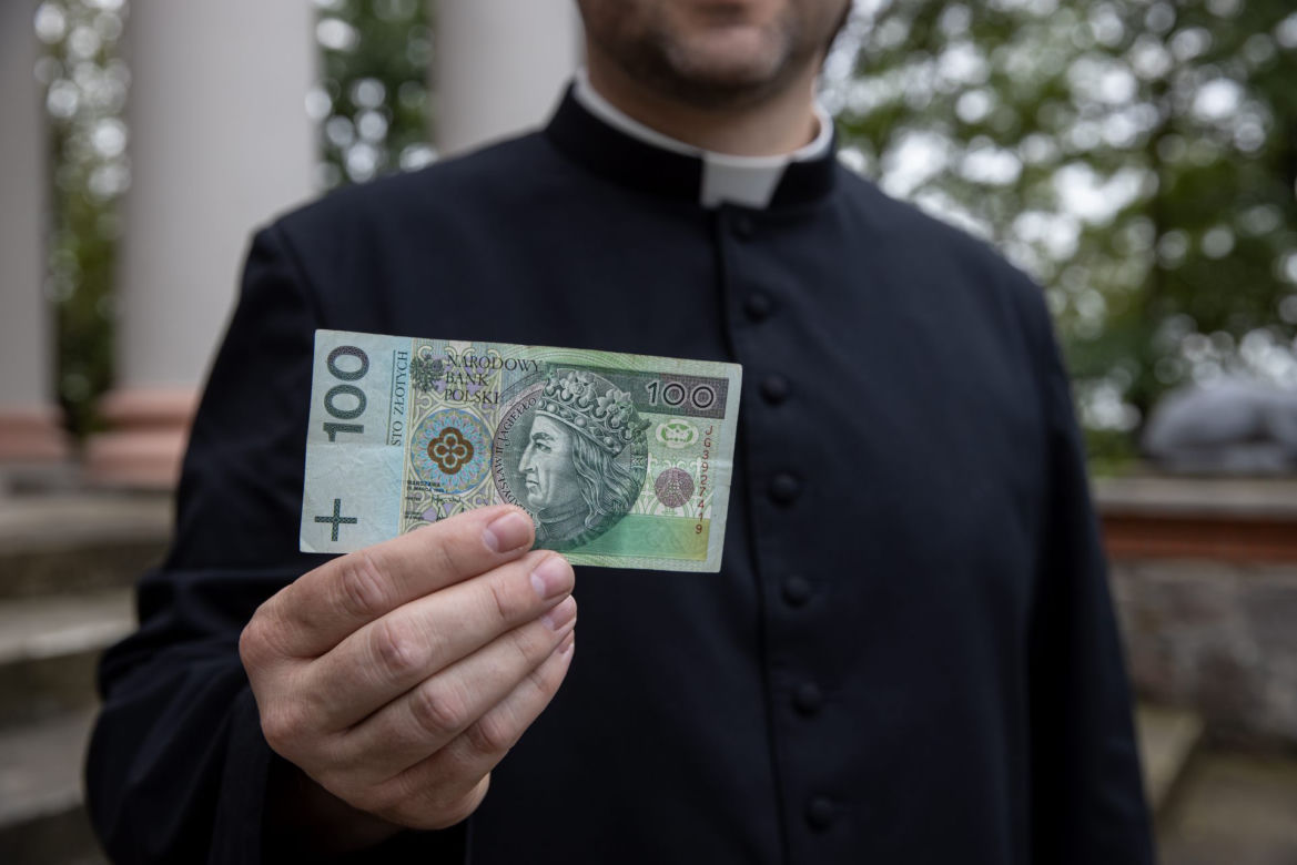 Ksiądz rozdaje pieniądze na mszy