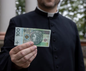 Ksiądz rozdaje pieniądze na mszy