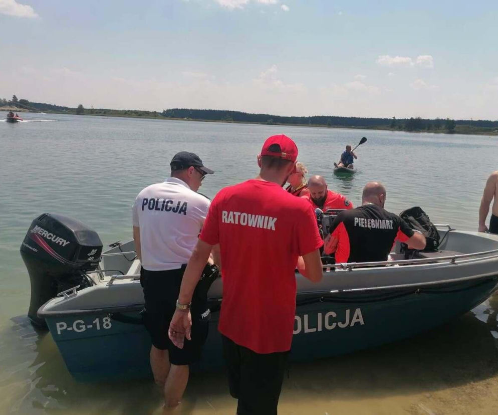 Ratownik w czerwonej koszulce i policjant z tyłu łodzi ratunkowej w trakcie akcji na zalewie w Radłowie, gdzie uratowano 24-latka. Możesz o tym przeczytać na naszym portalu.