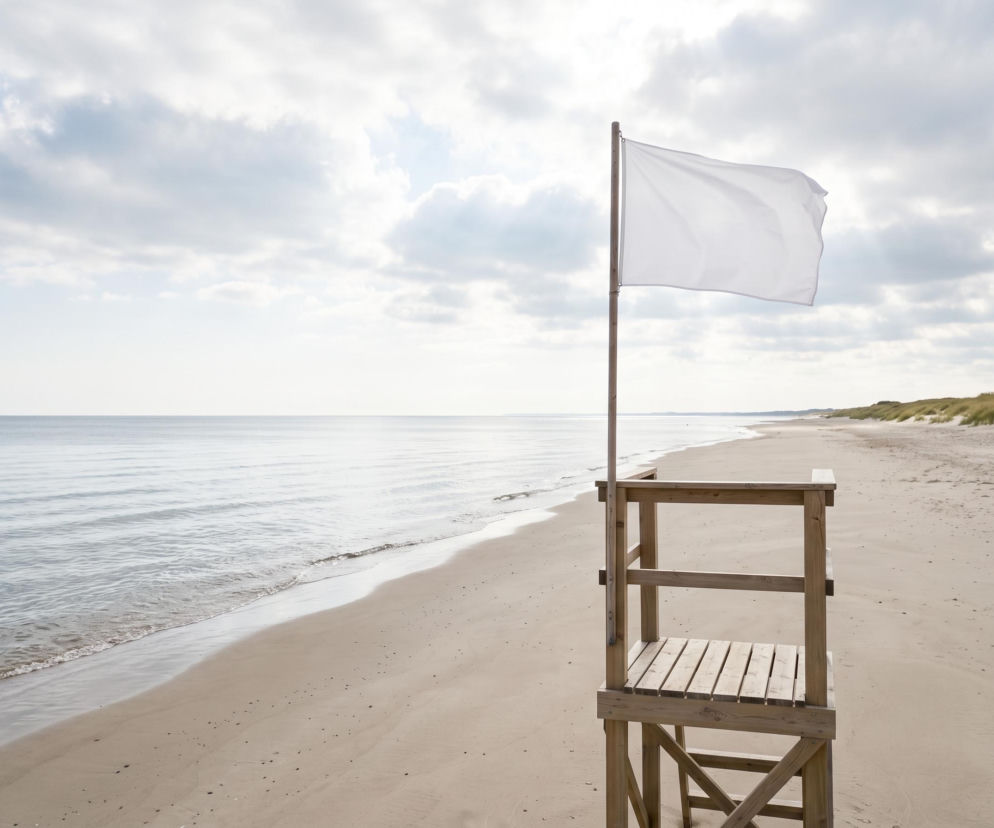 Biała flaga na wieży ratowniczej na pustej plaży w Świnoujściu. O bezpiecznych kąpielach przeczytasz na SE Szczecin.