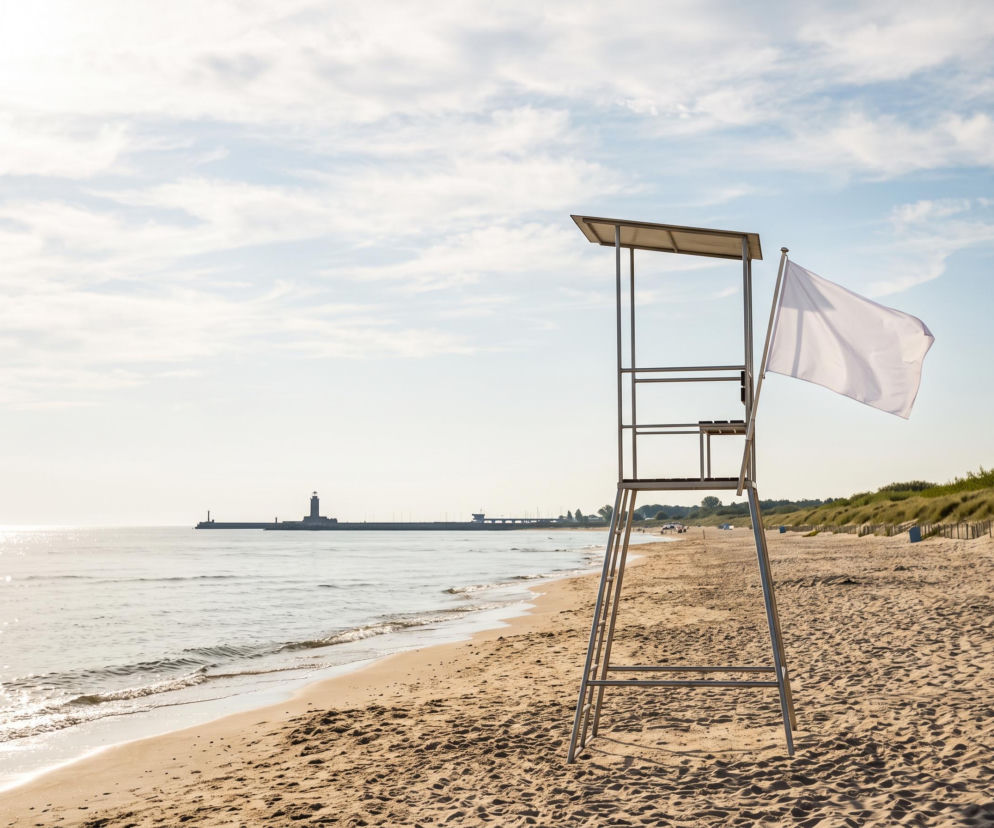 Wieża ratownicza z białą flagą na pustej plaży w Kołobrzegu. O bezpiecznych kąpieliskach przeczytasz na SE Szczecin.