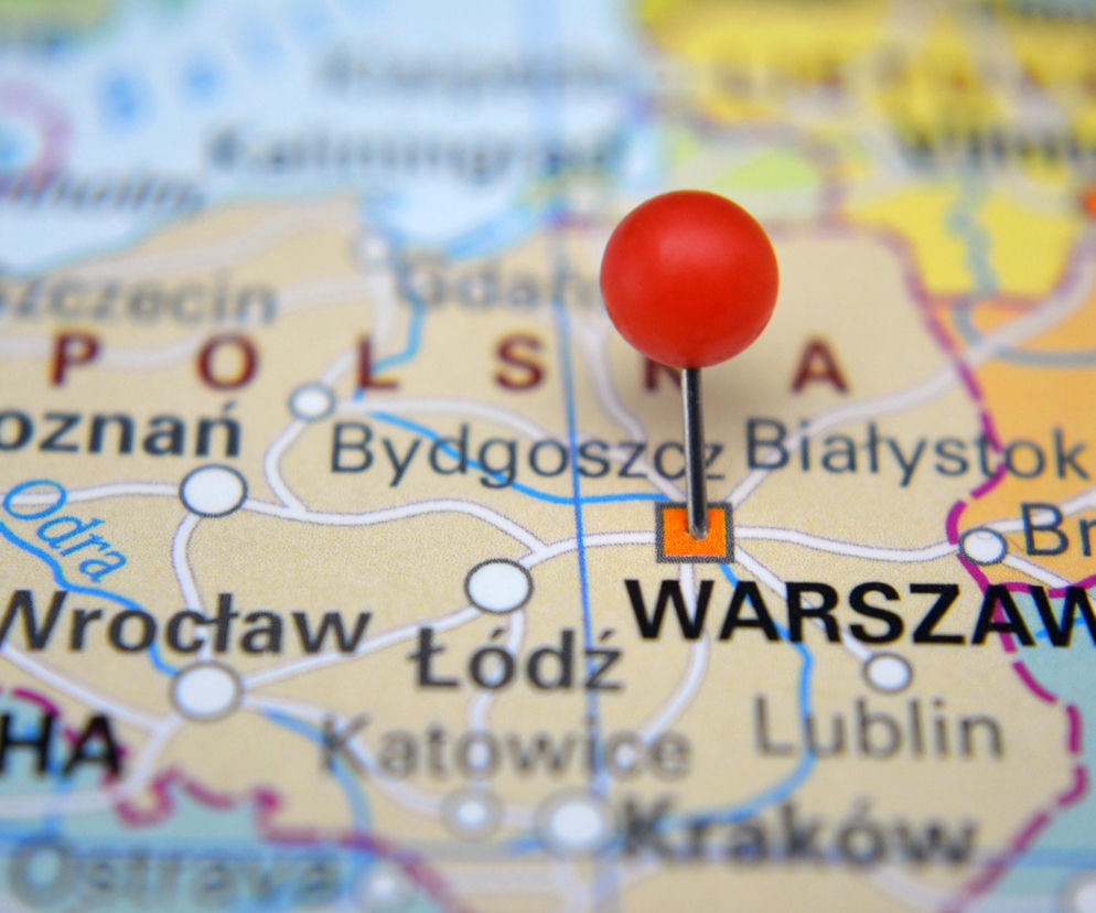Czerwona pinezka wbita w mapę Polski przy napisie Warszawa. O pożądanych miastach do życia przeczytasz na SE.