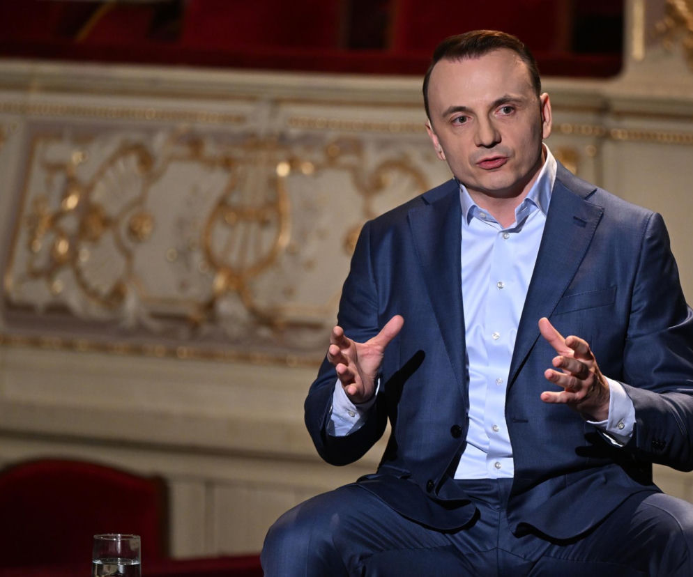 Łukasz Gibała w granatowym garniturze gestykuluje podczas rozmowy. O planach na zmiany w Krakowie czytaj w SE Polityka.