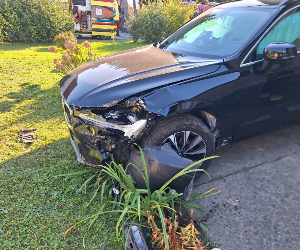 Czarny samochód z rozbitym przodem stoi na trawniku przed domem. O wypadku w Kąśnej Dolnej przeczytasz na Eska Tarnów.