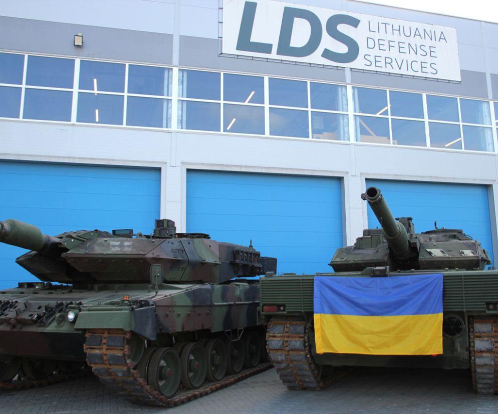 Dwa czołgi Leopard 2 przed halą z napisem LDS. Na jednym wisi flaga Ukrainy. O naprawie maszyn pisze SE Portal Obronny.
