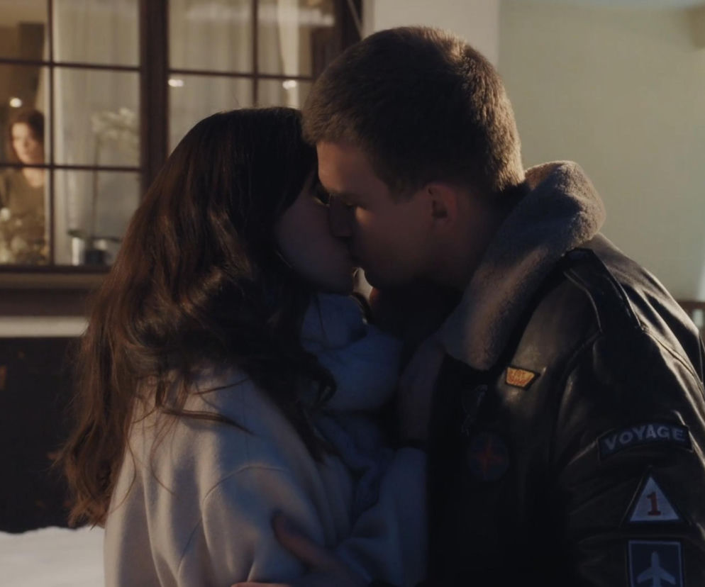 Namiętny pocałunek Bogny (Sherazade Wolff) i Mateusza (Rafał Kowalski) z serialu „M jak miłość” w zimowy wieczór. W tle, przez okno, zazdrosnym wzrokiem na parę patrzy Majka. Więcej o miłosnych perypetiach bohaterów przeczytasz na Super Seriale.