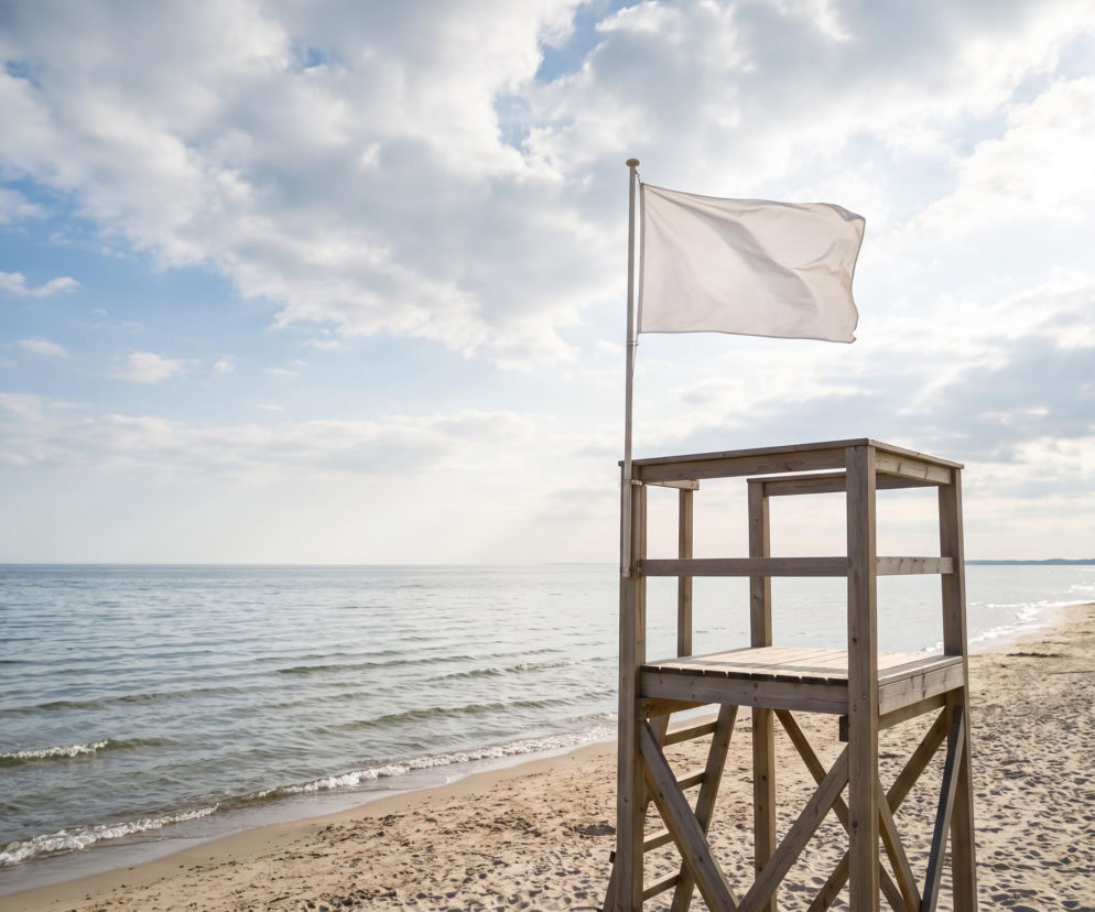 Biała flaga na wieży ratowniczej nad brzegiem Bałtyku w Dziwnowie. O warunkach na plażach przeczytasz na SE Szczecin.