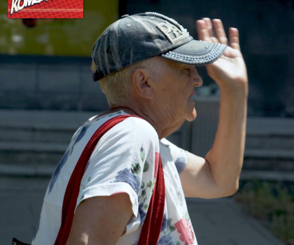 Seniorka machająca ręką na tle logotypu Komentery. O problemach w ochronie zdrowia przeczytasz na SE.
