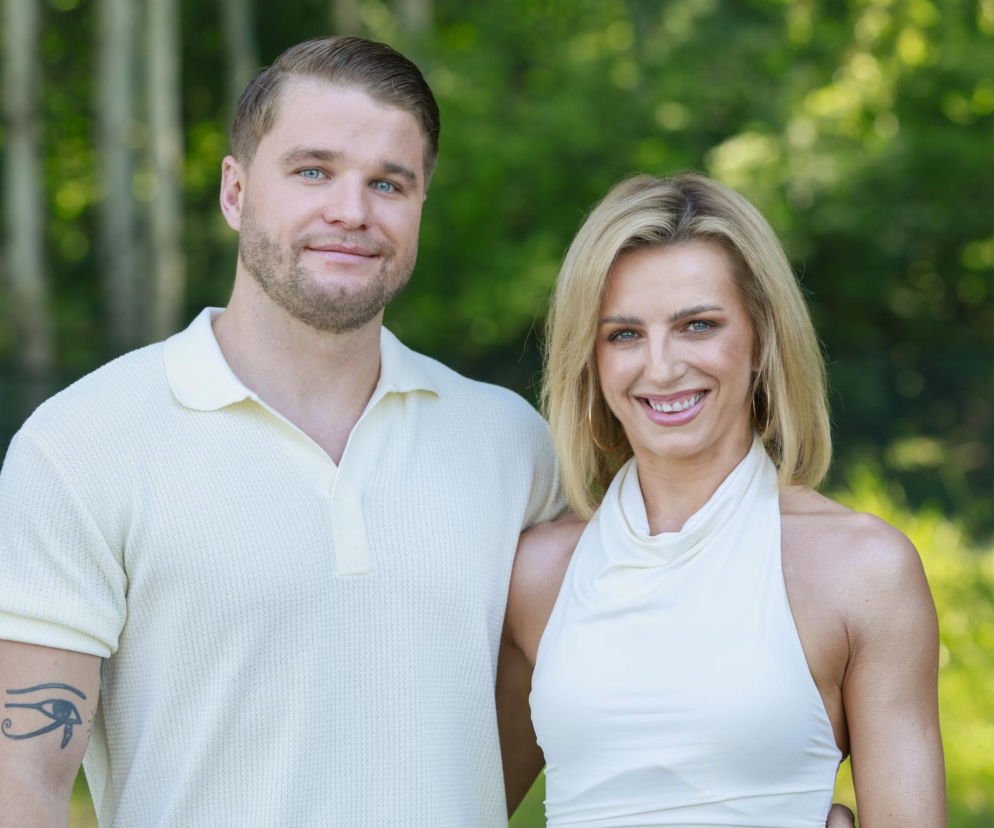Daria i Filip z Love is Blind: Polska uśmiechnięci pozują na tle zieleni. Mężczyzna w beżowej koszulce polo z tatuażem Oka Horusa na ramieniu, kobieta w białym topie, z blond włosami i kolczykami kołami. Czytelnicy mogą znaleźć więcej informacji o ich życiu po programie na naszym portalu.