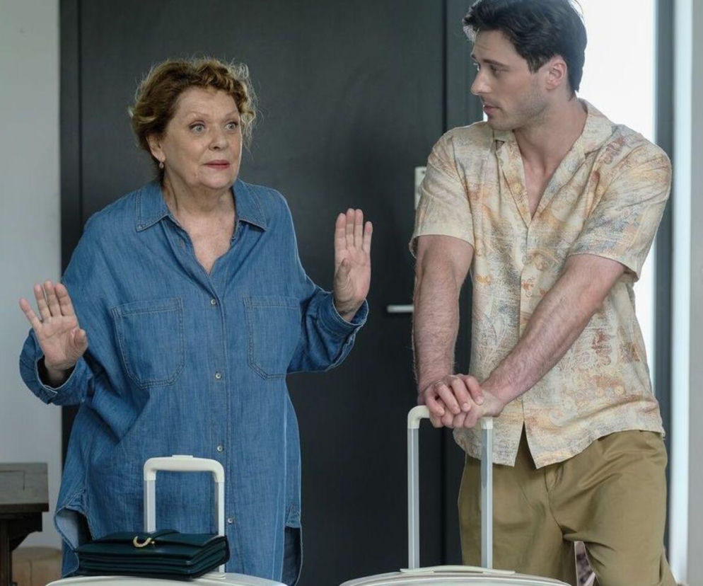 Józefina (Elżbieta Jarosik) z podniesionymi rękoma rozmawia z Cezarym (Marcel Opaliński), opierającym się o walizki, w scenie z serialu Barwy szczęścia, gdzie Józefina przeprowadza się do syna. Więcej o losach bohaterów na Super Seriale.