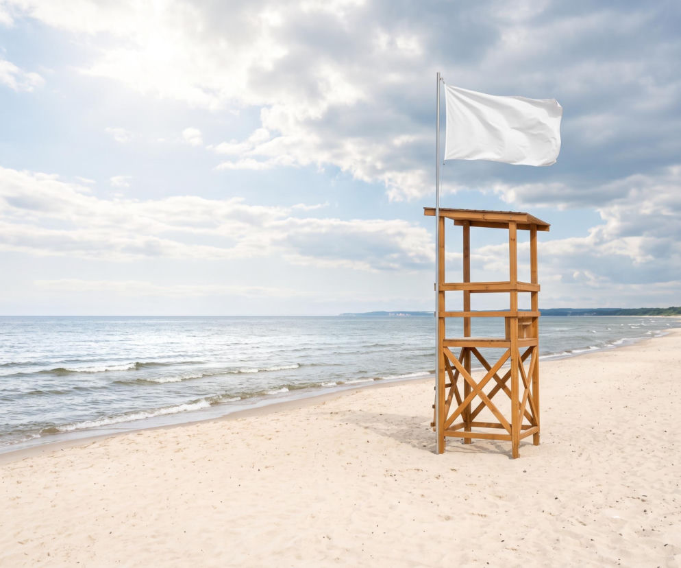 Drewniana wieża ratownika z białą flagą na plaży w Sarbinowie. O bezpiecznej kąpieli przeczytasz na SE Szczecin.