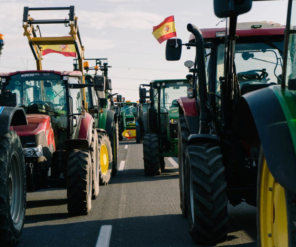 Kolumna ciągników z hiszpańskimi flagami jadąca drogą podczas protestu rolników. O szczegółach przeczytasz na SE Superbiz.