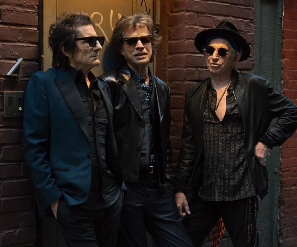 Muzycy The Rolling Stones na tle ceglanej ściany. O filmowej biografii zespołu przeczytasz na EskaRock.
