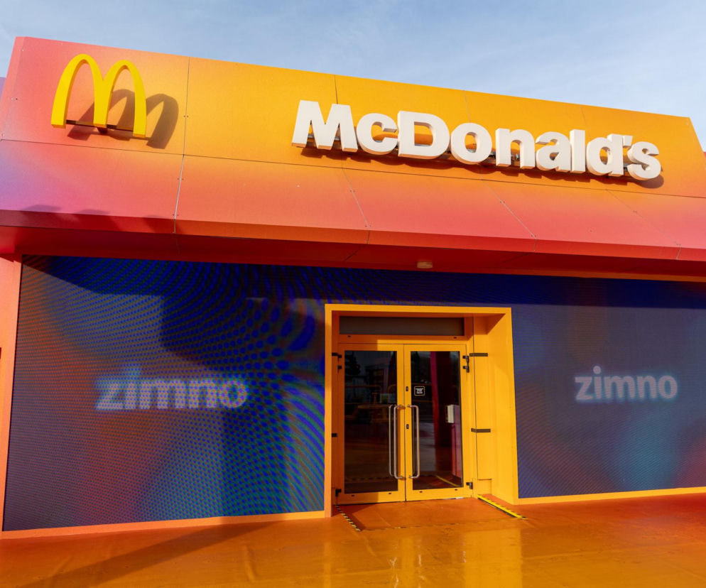 Fasada restauracji McDonald's z wielkim żółtym logo M i napisem McDonald's na pomarańczowym tle. Przed wejściem świecą się ekrany z napisem zimno, wskazując na premierę burgera Drwala lub nowego Big Arch, o czym więcej przeczytasz na Super Biznes.