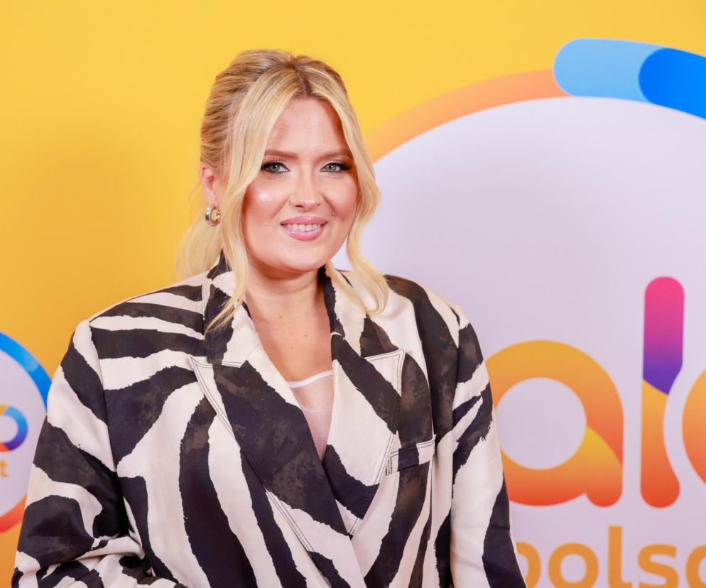Uśmiechnięta Gosia Andrzejewicz w marynarce w zebrę na tle logo halo tu polsat. O powrocie gwiazdy przeczytasz na SE.