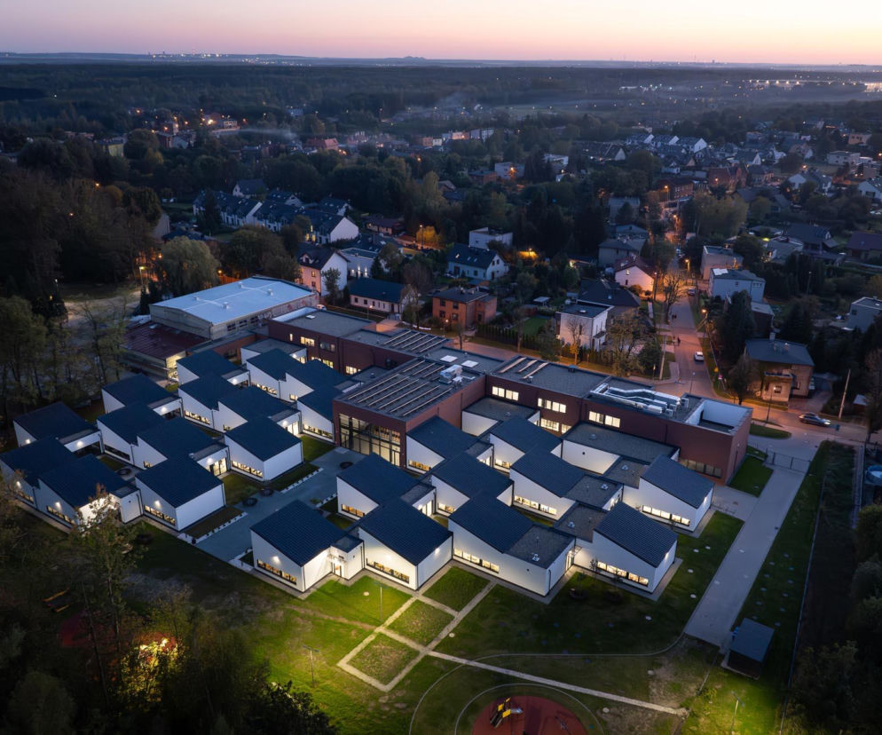 Oświetlony kompleks szkolny w Rudzie Śląskiej po zmroku. O nowej architekturze szkół przeczytasz na portalu Architektura.