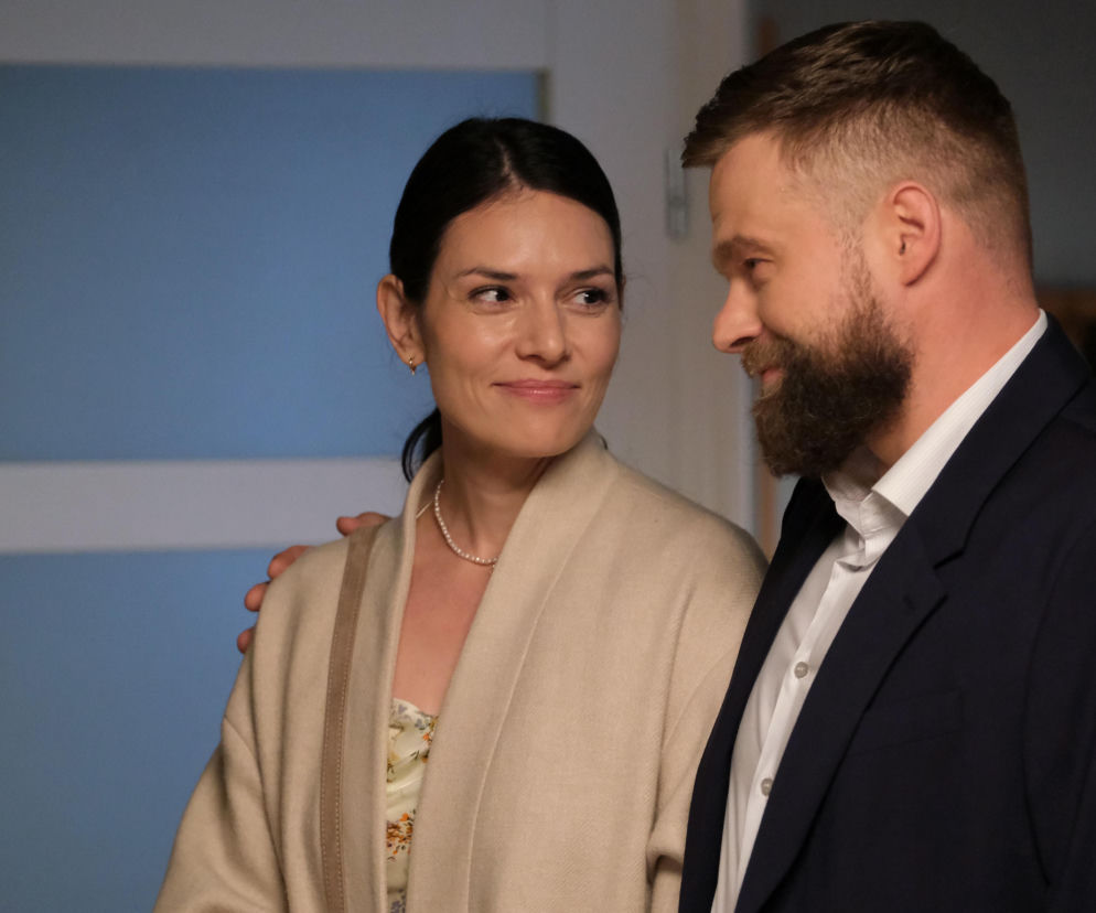 Ewelina (Anna Jarosik) i Michał (Tomasz Rożniatowski) z M jak miłość stoją blisko siebie, patrząc na siebie z uśmiechem. Kobieta ma na szyi perłowy naszyjnik, a mężczyzna ciemną marynarkę. Więcej o ich losach w M jak miłość na portalu Super Seriale.