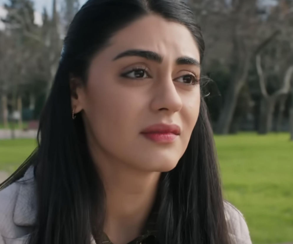 Młoda kobieta, Hancer, z długimi ciemnymi włosami, w jasnej kurtce, patrzy w dal z zatroskaną miną. Scena z serialu Panna młoda, gdzie Hancer po ślubie ucieka od Cihana i opuszcza rezydencję. Więcej o dramatycznych losach bohaterów przeczytasz na Super Seriale.