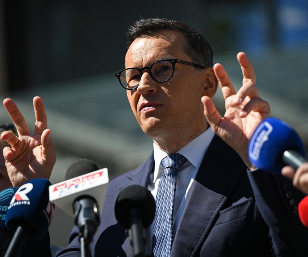 Mateusz Morawiecki w okularach, w granatowym garniturze i krawacie, gestykulujący dłońmi podczas konferencji prasowej przed Szpitalem Południowym, z widocznymi mikrofonami różnych stacji telewizyjnych. Więcej o tej sprawie przeczytasz na naszym portalu.