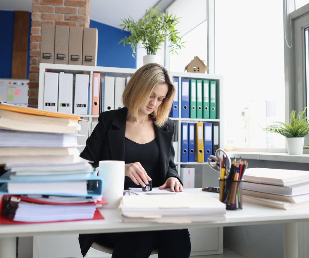Urzędniczka przy biurku pełnym dokumentów