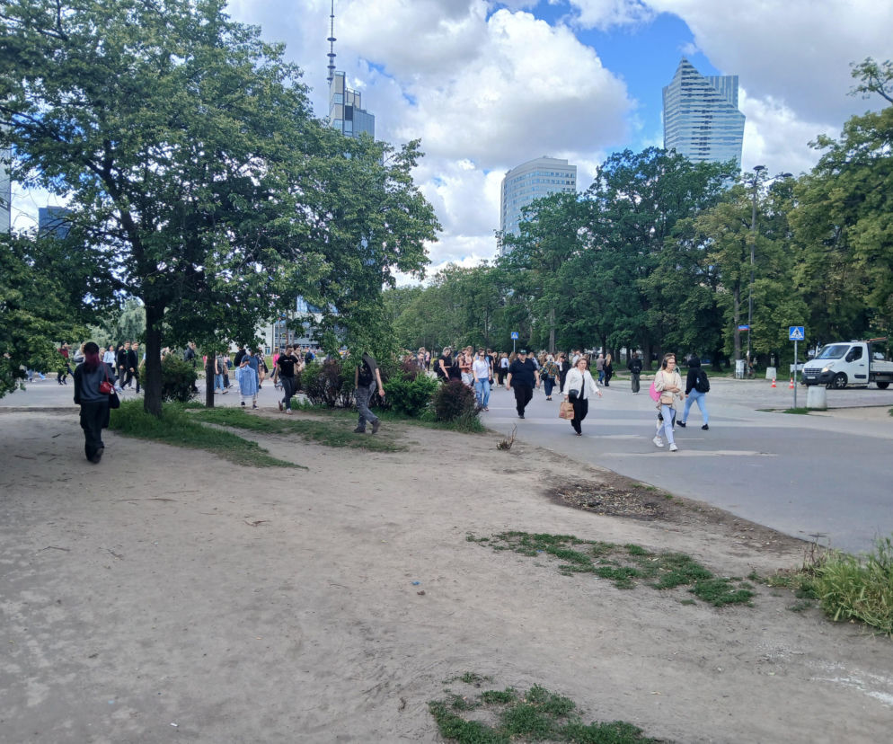Ludzie idą wydeptaną ścieżką obok chodnika przy metrze Centrum w Warszawie. O planach zmian przeczytasz na Architektura.