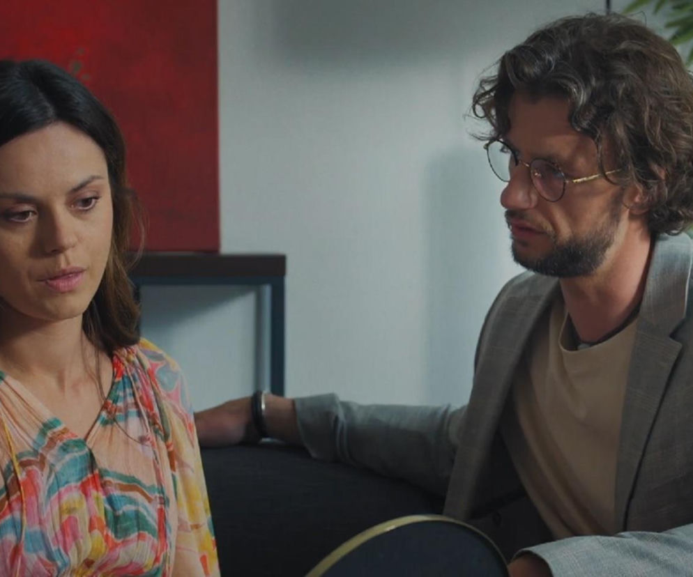 Paulina Lasota jako Kasia i Mateusz Mosiewicz jako Mariusz w scenie z serialu M jak miłość. Kobieta, ubrana w kwiecistą sukienkę, patrzy ze smutkiem w dół, podczas gdy mężczyzna w okularach i szarej marynarce spogląda w jej stronę. Więcej informacji o serialu znajdziesz na Super Seriale.