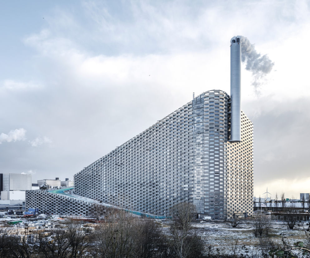 Nowoczesna spalarnia CopenHill w Kopenhadze z ukośnym dachem pełniącym funkcję stoku narciarskiego i kominem emitującym parę wodną, co doskonale wpisuje się w ekologiczne rozwiązania opisywane na portalu Architektura Murator Plus.