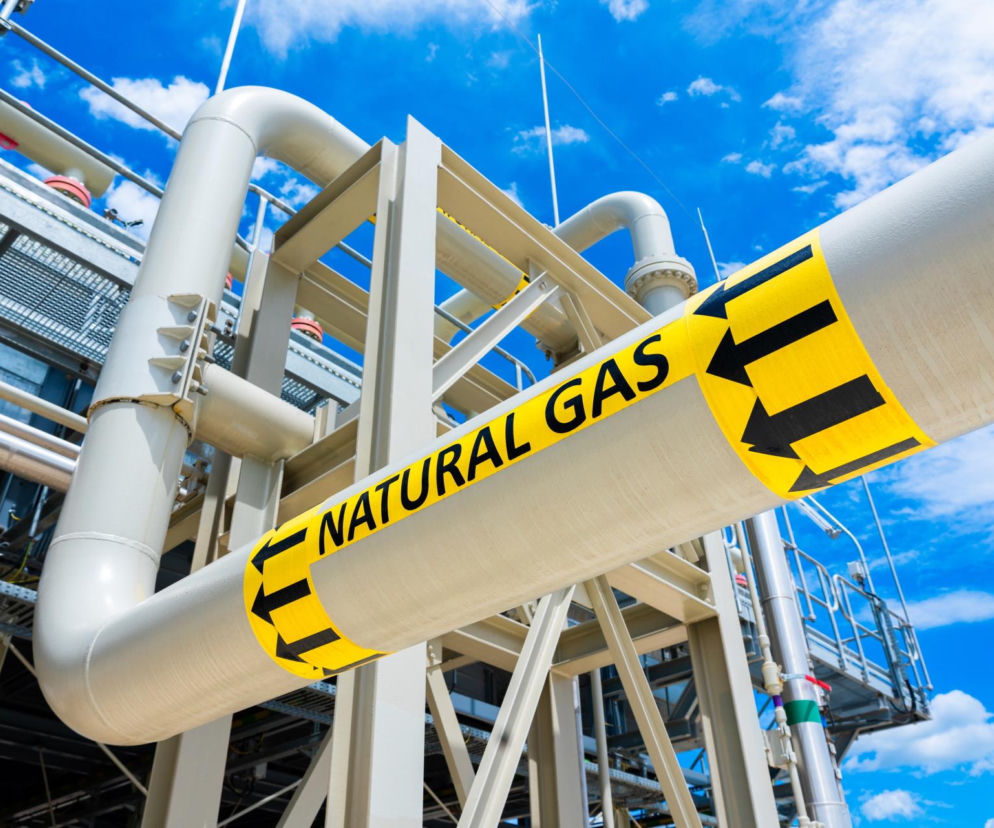 Rury gazowe z napisem NATURAL GAS na tle nieba. O rosnących cenach gazu w 2026 roku przeczytasz na SE Superbiz.
