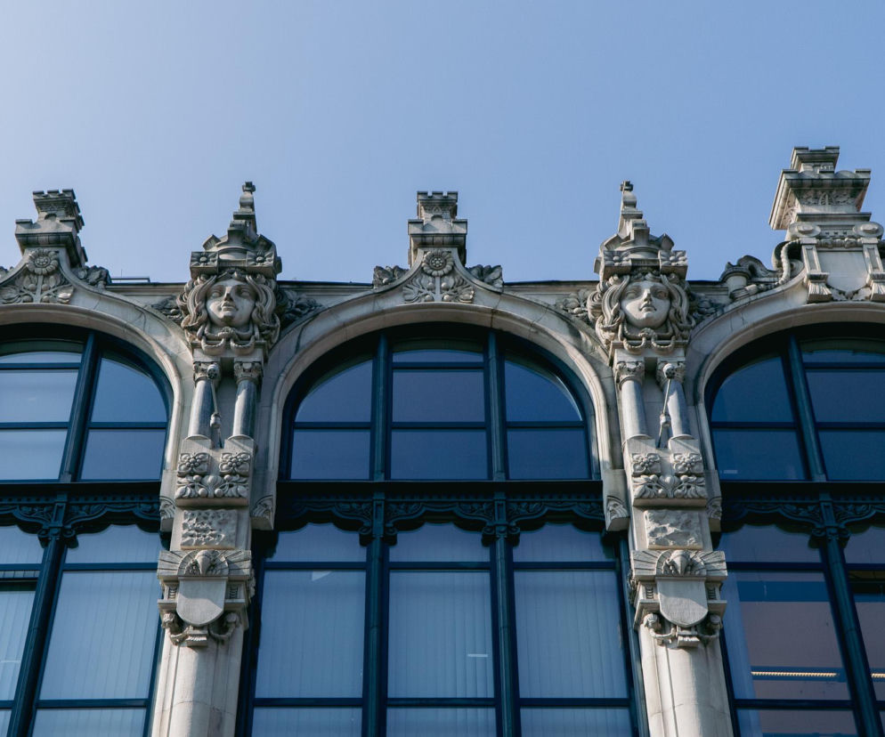 Kamienica Pod Gorgoną we Wrocławiu, z charakterystycznymi secesyjnymi zdobieniami architektonicznymi. Detale rzeźbionych głów i roślinnych motywów nad oknami świadczą o luksusie dawnych domów handlowych, o których więcej na Architektura Murator Plus.