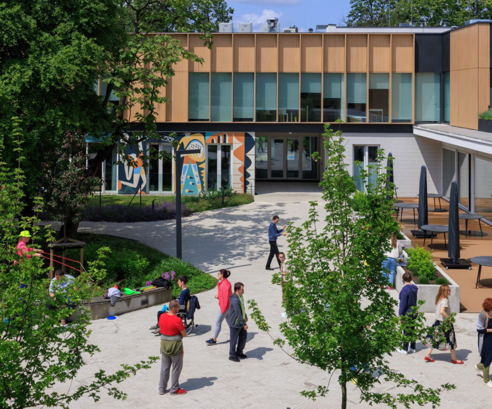 Nowoczesne Centrum Aktywności Międzypokoleniowej na warszawskiej Ochocie, wyróżnione w konkursie Życie w Architekturze. Obiekt autorstwa pracowni xystudio z elewacjami w odcieniach drewna i szarości, z zielonym patio i kolorowymi muralami, gdzie spotykają się użytkownicy w różnym wieku, stanowi przykład innowacyjnego podejścia do przestrzeni publicznej, o czym więcej przeczytasz na Architektura Murator Plus.