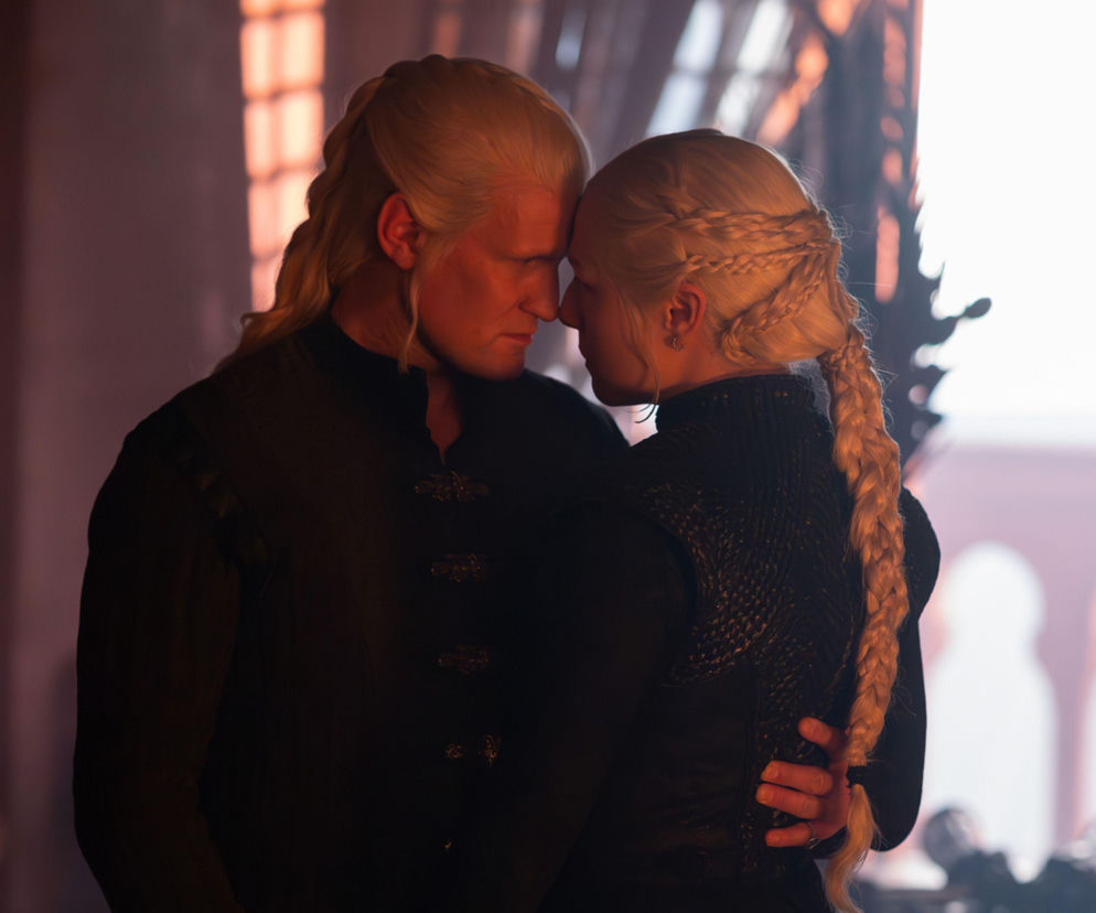Daemon Targaryen i Rhaenyra Targaryen z serialu Ród smoka w intymnym uścisku, z włosami koloru platynowego. Postacie stoją blisko siebie, ich czoła stykają się, symbolizując bliskość. Więcej o ich losach przeczytasz na portalu Super Seriale.