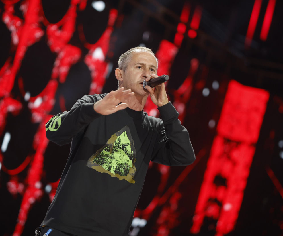 Raper Eldo podczas występu na scenie trzyma mikrofon przy ustach. O kulisach jego współpracy z prezydentem przeczytasz na SE.