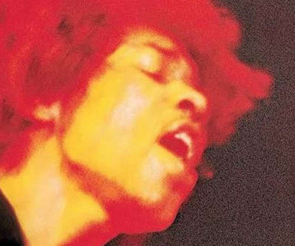 Gitarzysta Jimi Hendrix z przymkniętymi oczami na pomarańczowo-czerwonym zdjęciu. O artyście przeczytasz na EskaRock.