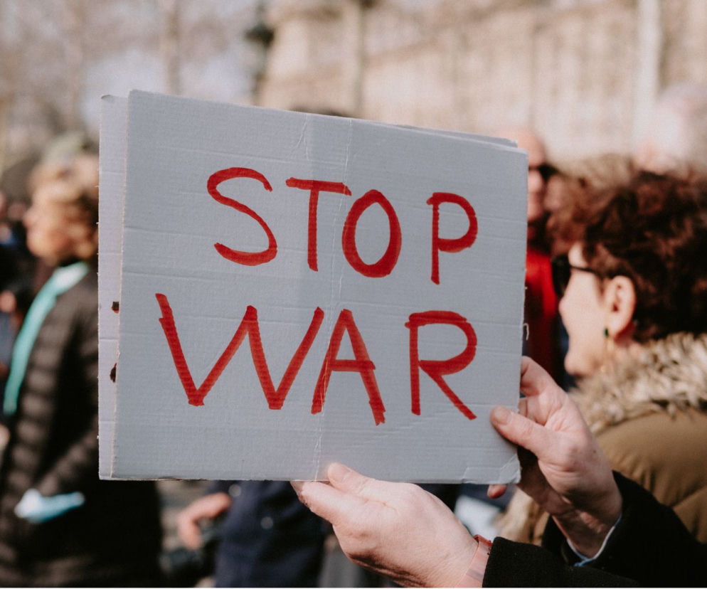 Dłonie osoby trzymającej kartonowy transparent z czerwonym napisem STOP WAR. O zagrożeniu atakiem Rosji przeczytasz na SE Portal Obronny.