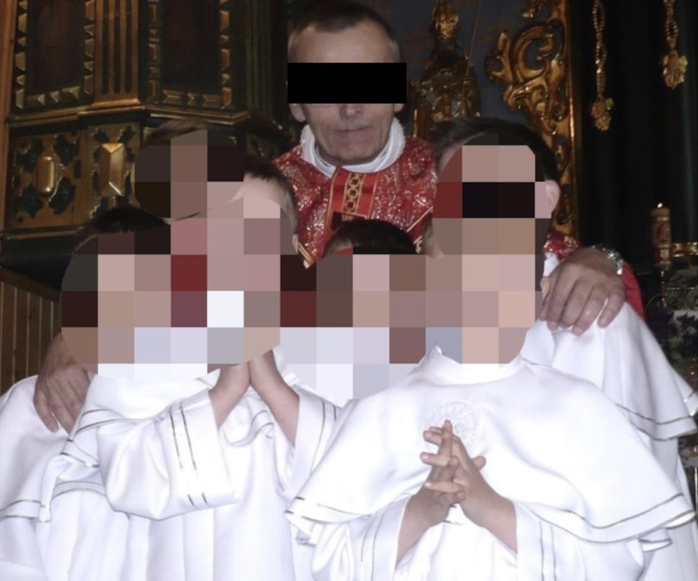 Ksiądz Jacek K. w szatach liturgicznych obejmuje grupę dzieci w kościele. O wyroku dla duchownego przeczytasz na SE.