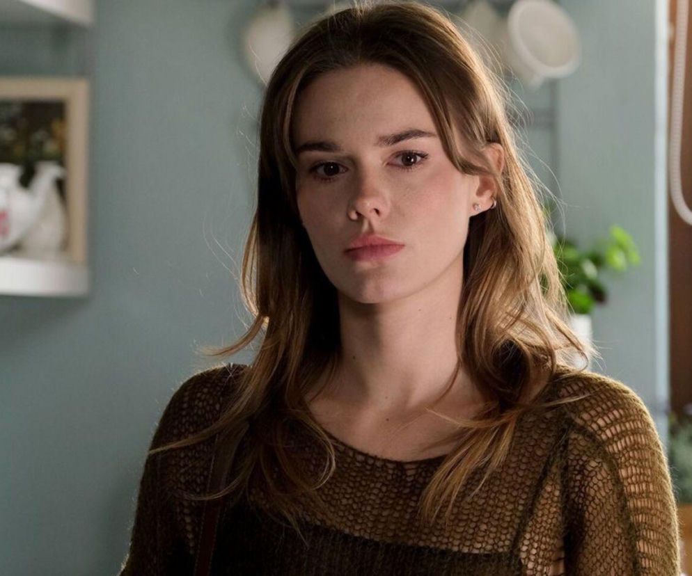 Portret Dominiki Kachlik, aktorki znanej z roli Franki w M jak miłość, w brązowym swetrze. Wygląda na zamyśloną, z lekko rozpuszczonymi włosami, na tle jasnego wnętrza kuchni. Artykuł na Super Seriale informuje o powrocie jej postaci do serialu po śmierci.