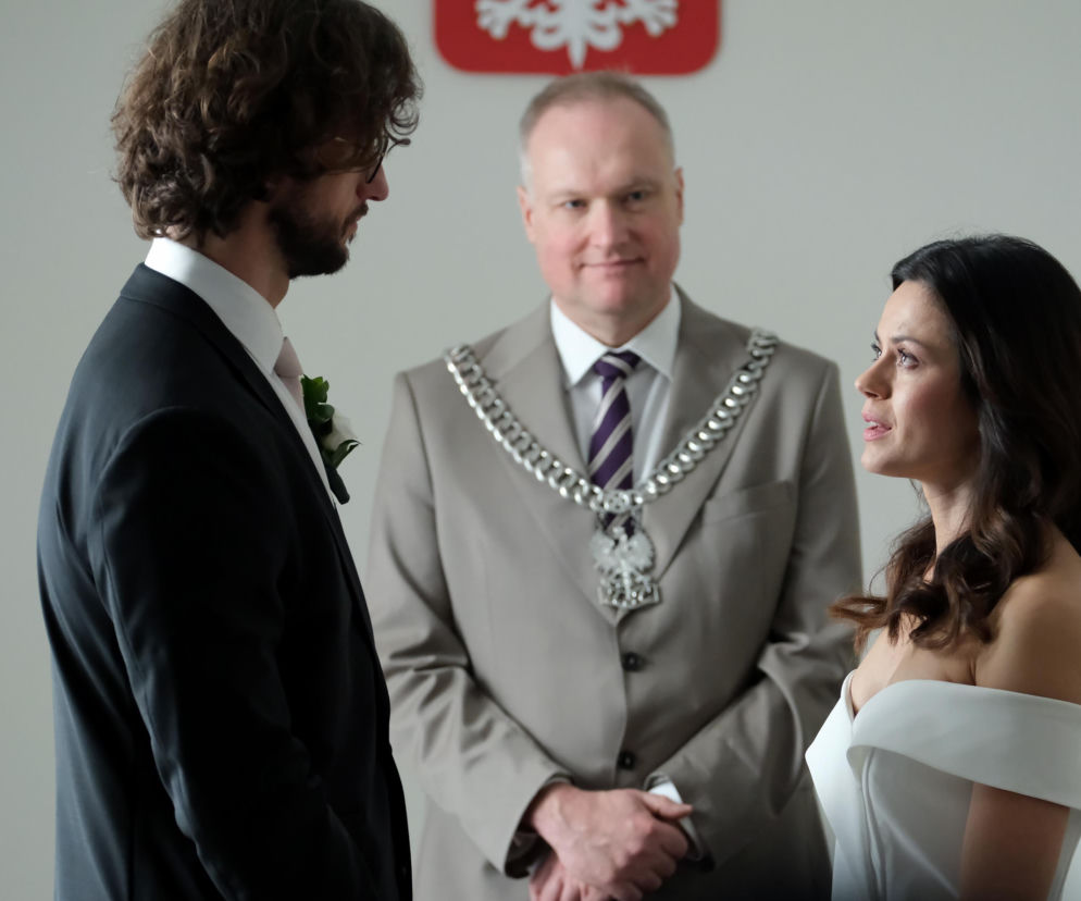 Paulina Lasota (Kasia) i Mateusz Mosiewicz (Mariusz) stoją przed urzędnikiem stanu cywilnego (Krzysztof Kwiatkowski) podczas ceremonii ślubnej w „M jak miłość”. Scena ukazuje parę podczas składania przysięgi małżeńskiej. O wszystkich wydarzeniach przeczytasz na portalu Super Seriale.