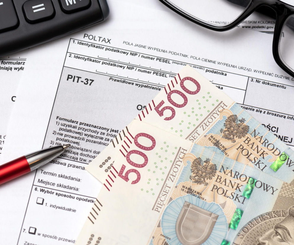 Formularz PIT-37, kalkulator, długopis i okulary, oraz banknoty 500 zł. Materiał o zwrotach podatku dla emerytów i rencistów znajdziesz na Super Biznes.