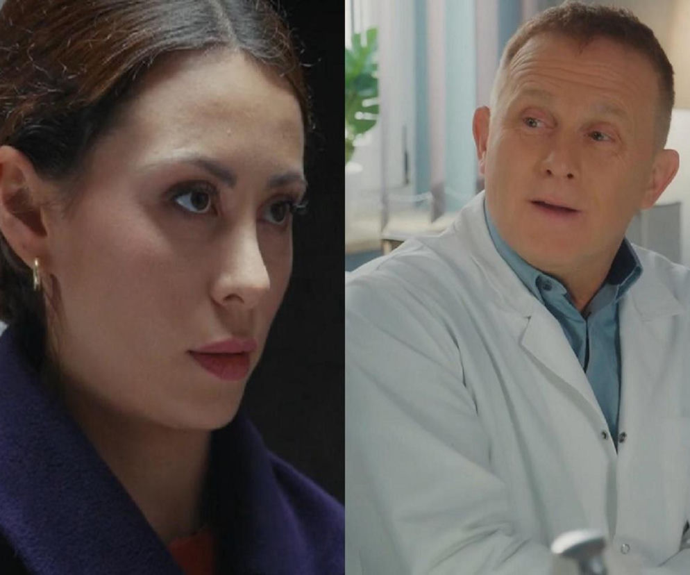 Joanna (Dominika Sakowicz) w ciemnym płaszczu z kołnierzem patrzy w bok, z zamyśloną miną, obok Artur Rogowski (Robert Moskwa) w białym kitlu i błękitnej koszuli. Scena z serialu M jak miłość, odcinek 1921. Więcej na ten temat znajdziesz na Super Seriale.