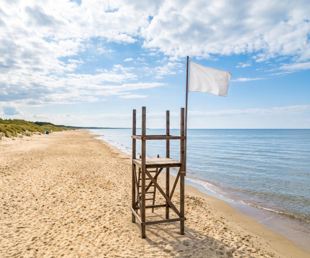 Drewniana wieża ratownicza z białą flagą na pustej plaży w Międzyzdrojach. O bezpieczeństwie nad wodą czytaj w SE Szczecin.